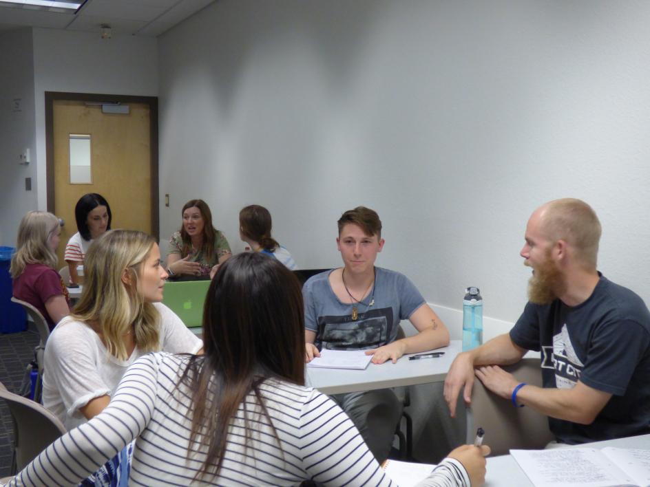 Students around a table having a classroom discussion.