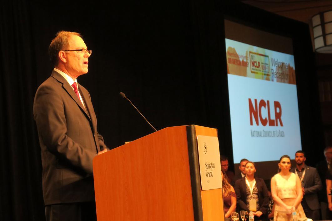 A man speaks at a lectern.