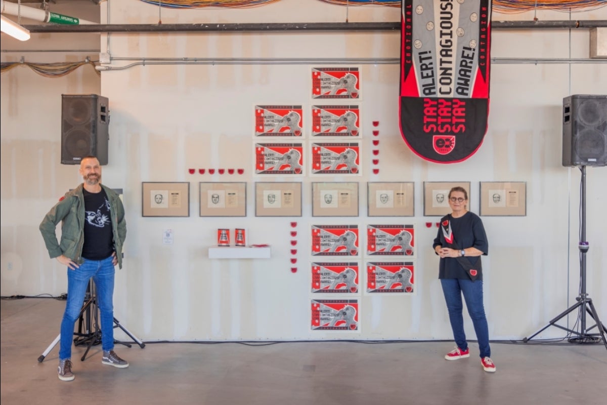 Two people standing in front of a wall displaying works of art.