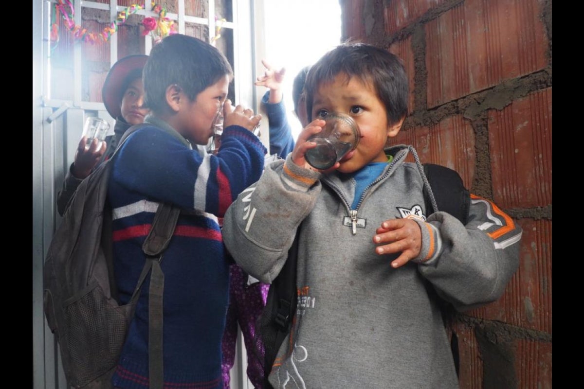 The kids from Huillcapata try the new filtered water during the education event.