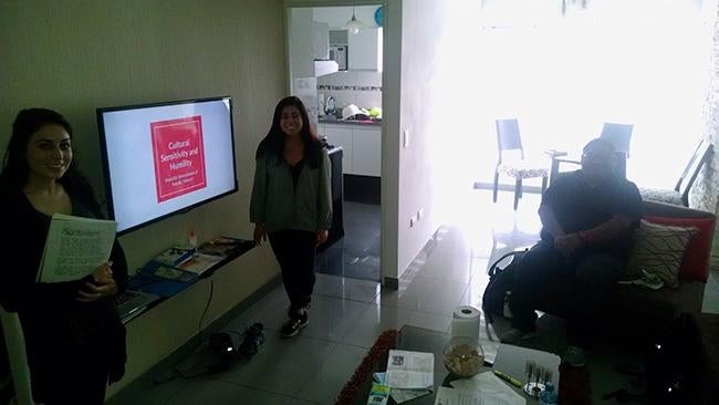 Three people are pictured in a community center in Peru preparing for a presentation