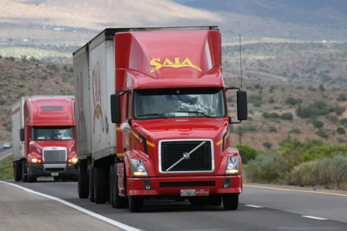 Two semitrucks driving on a two-lane highway.