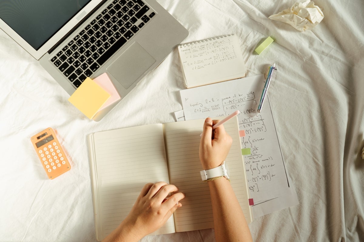 Person working on school work in bed