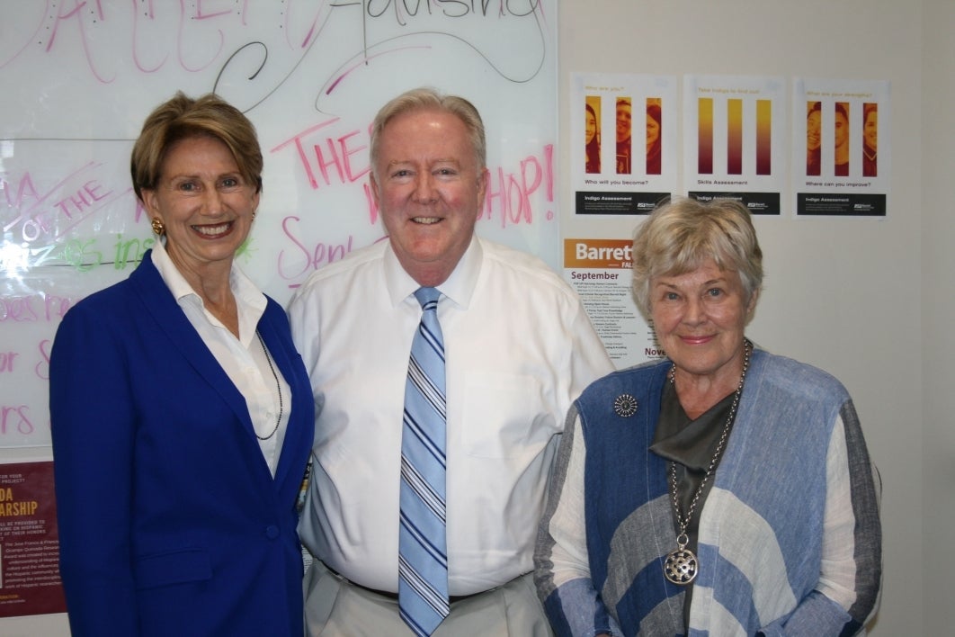 Three people pose for a photo in front of a whiteboard.