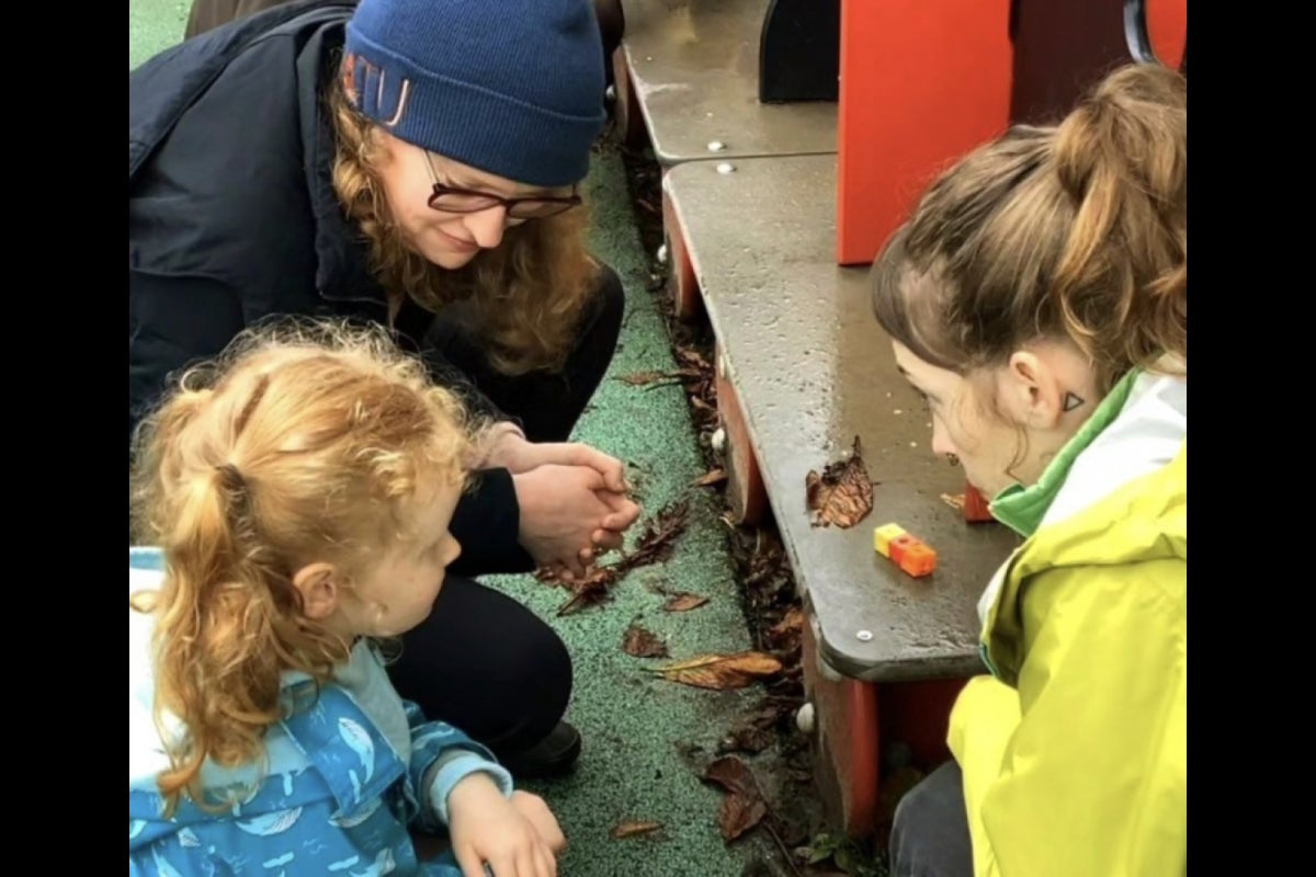 Two adults and a child kneeling and looking at one another.