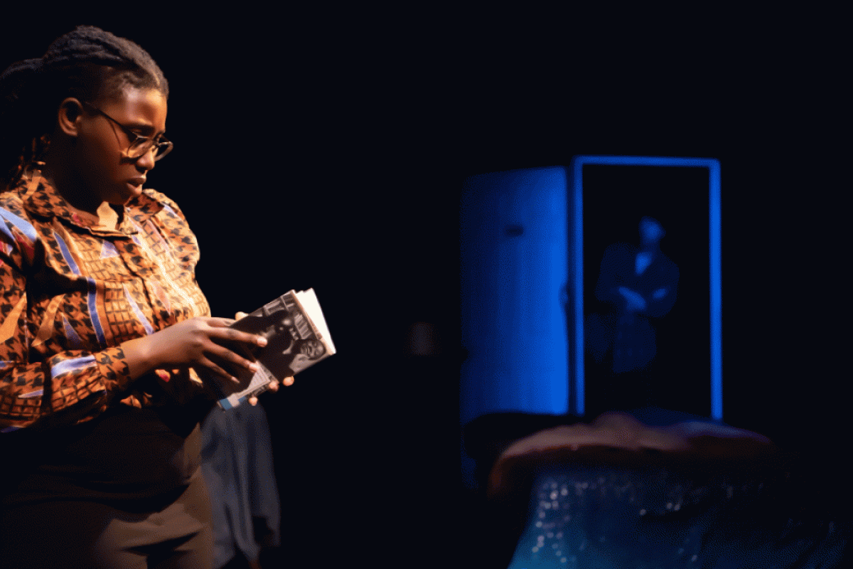 Woman on a stage holding a play booklet.