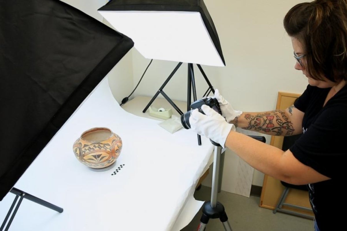 A student documents a pot with a camera.