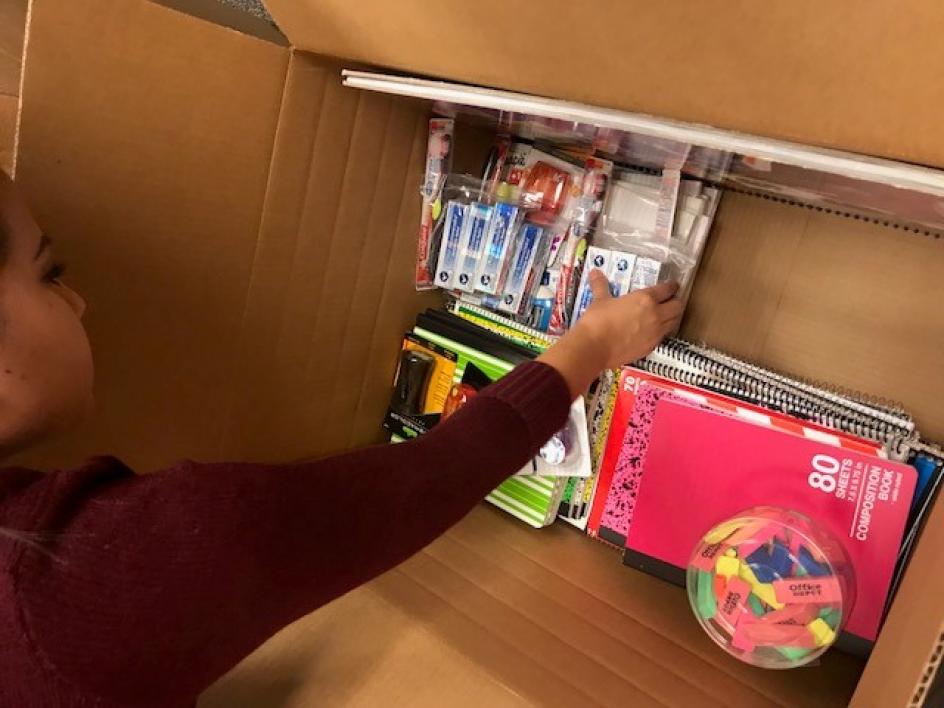 woman packing school supplies into box