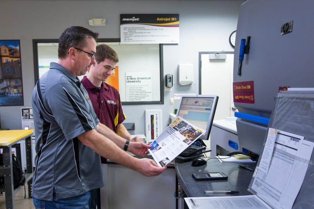 two people looking at printed paper