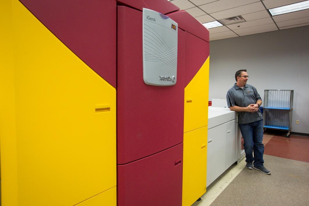 man standing next to large printer