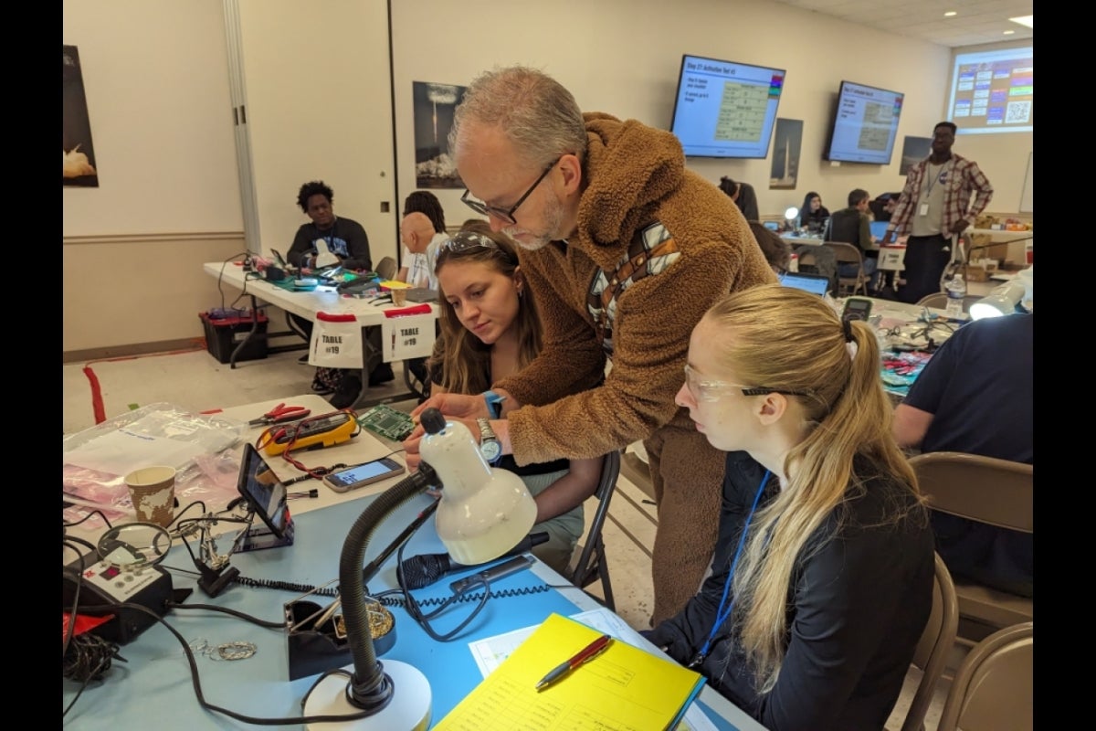 Students at a table watching an instructor.