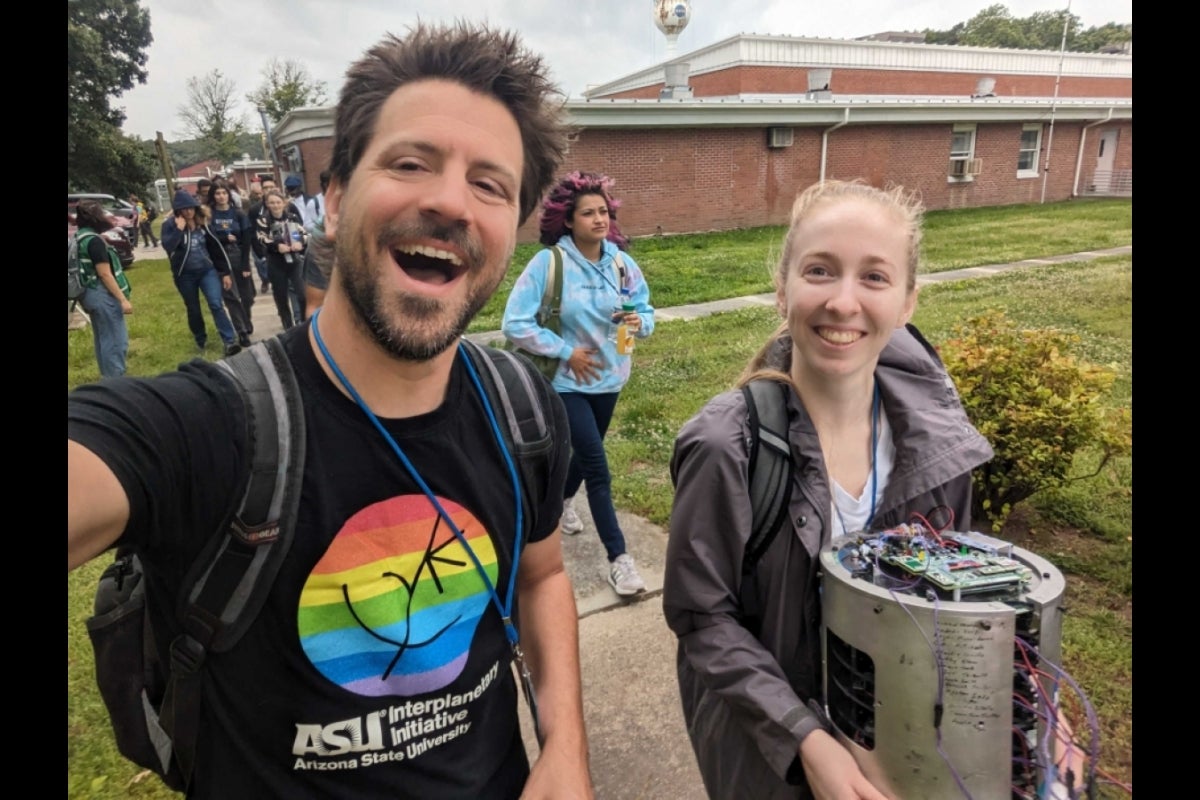 A professor and a student smiling at the camera.