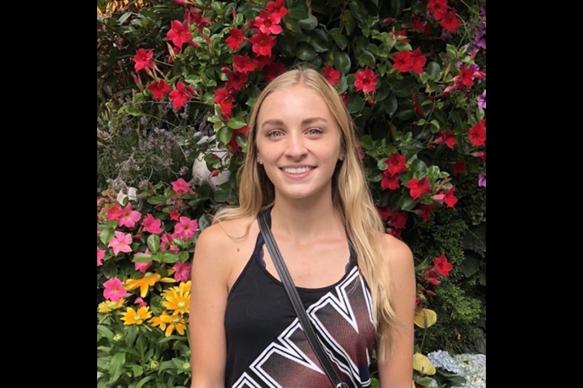 portrait of woman in front of flower bushes