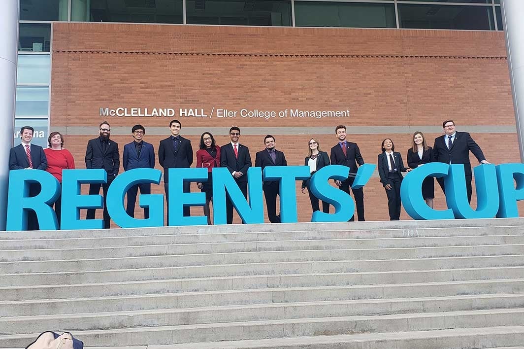 Students stand behind a sign that reads: 