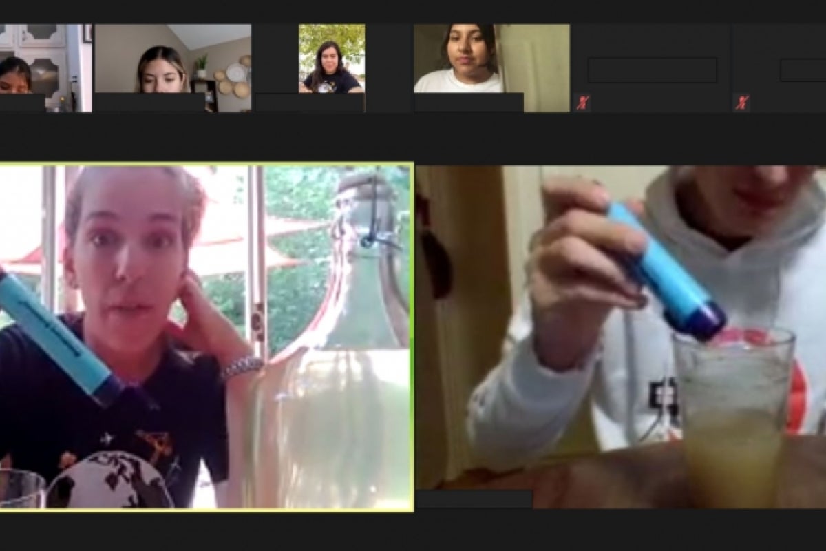 A Zoom screenshot in which Lecturer Mackenzie Boyer and a SEE@ASU participant are holding water filtration devices next to a container of dirty water.