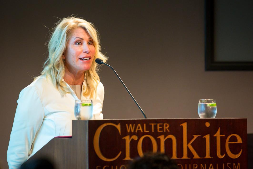 A woman speaks behind a lectern.