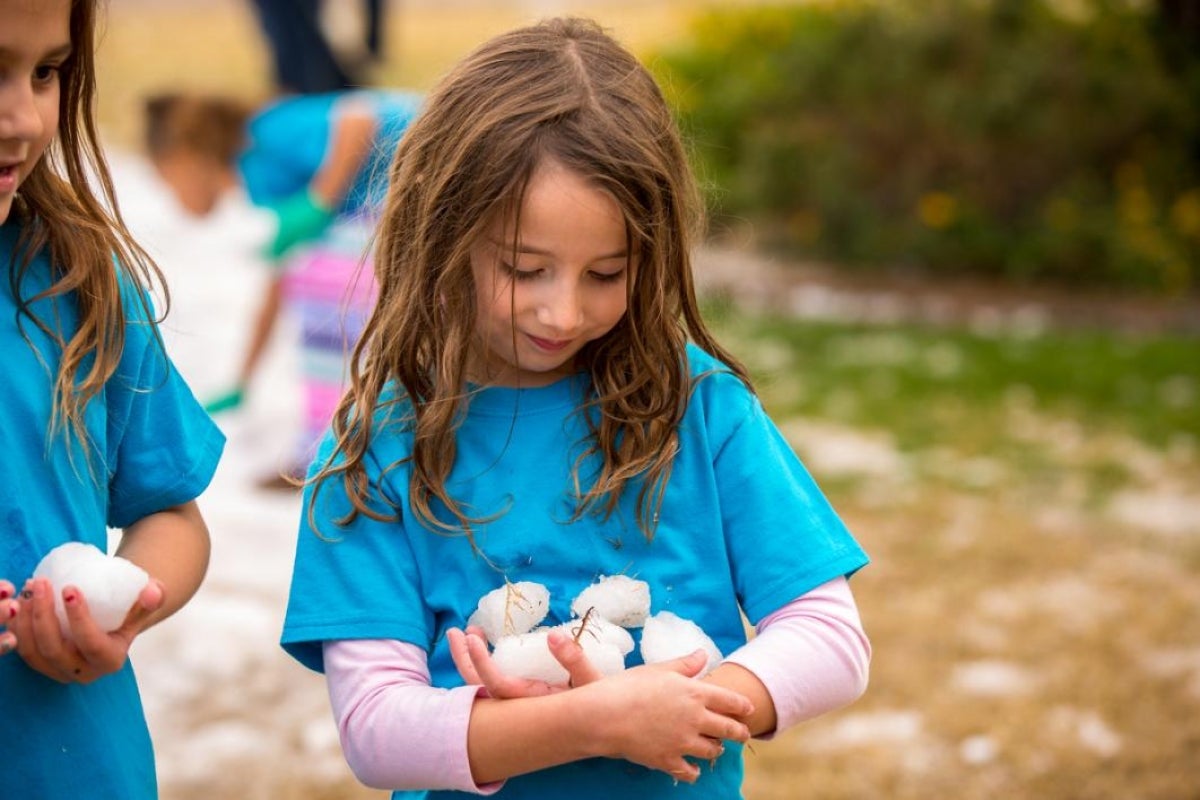 A girl holds snowballs.