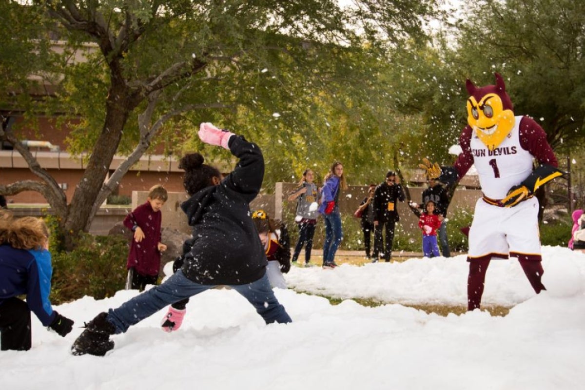 Children pelt a mascot with snowballs.