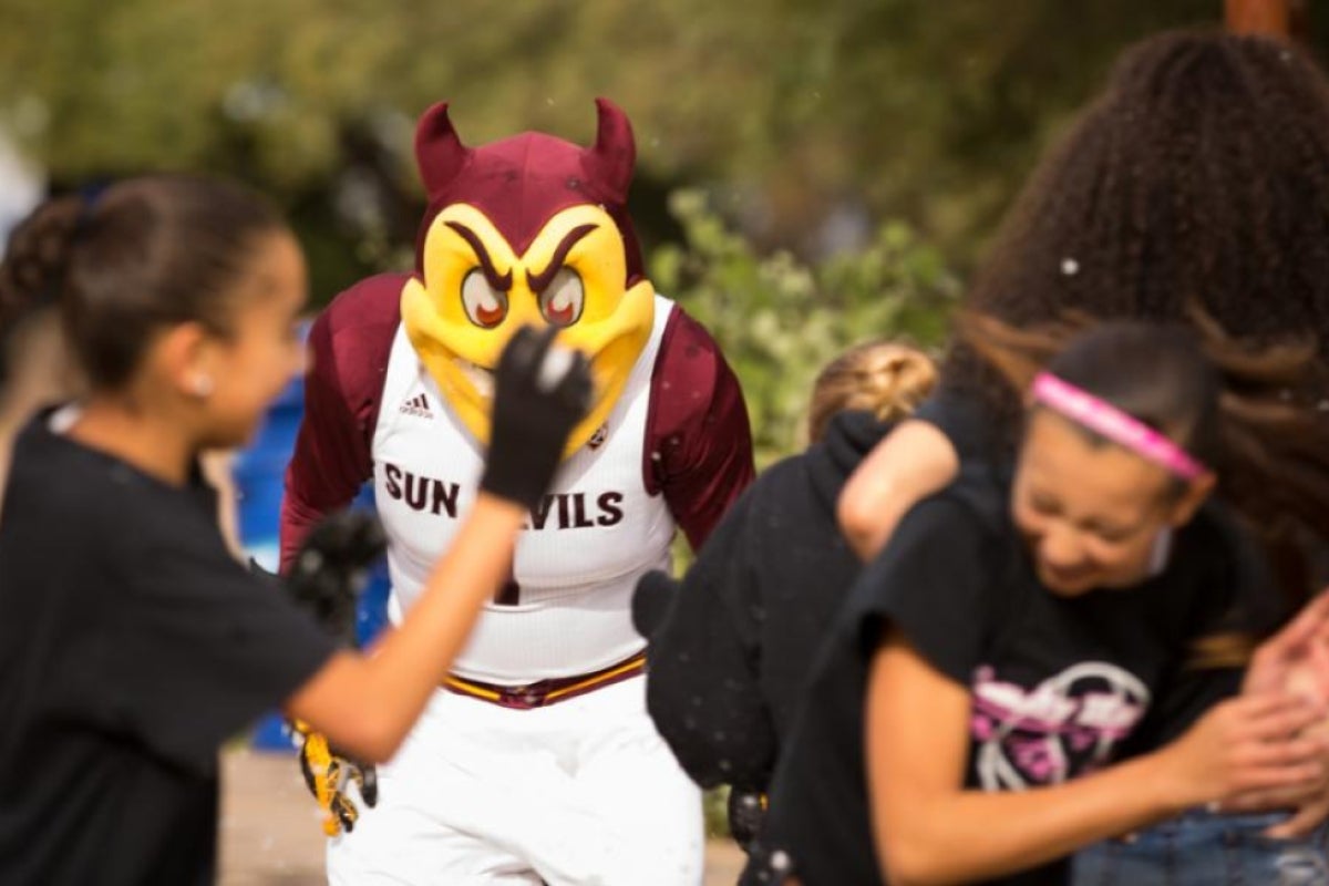 People throwing snowballs at a mascot.