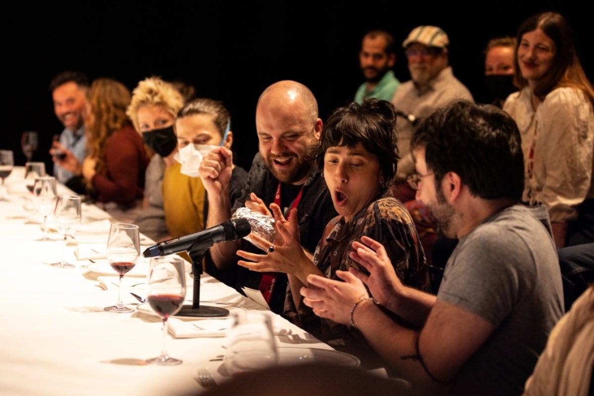 People seated at a long table making surprised expressions.