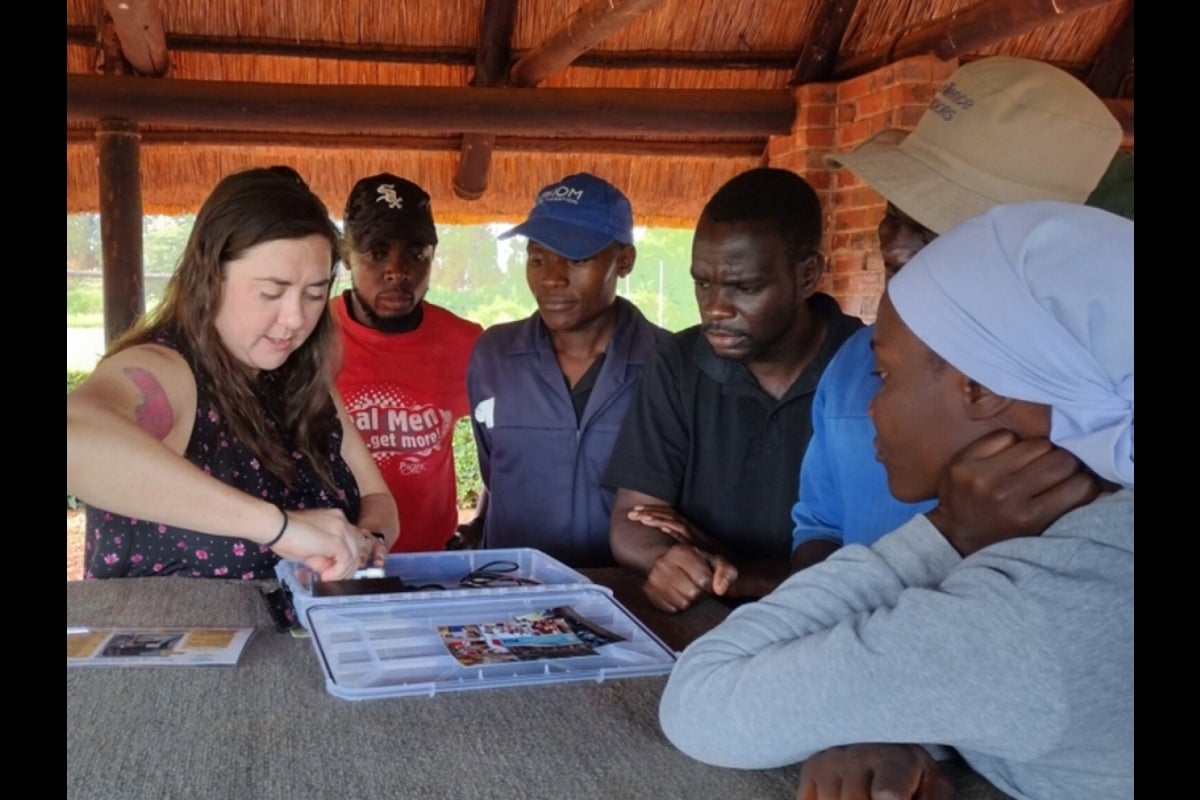 Woman showing group in Africa how to set up solar-powered library