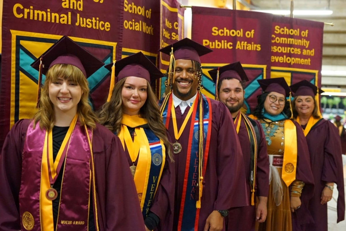 Graduates of ASU's Watts College of Public Service and Community Solutions wear graduation regalia and stand at their graduation ceremony.