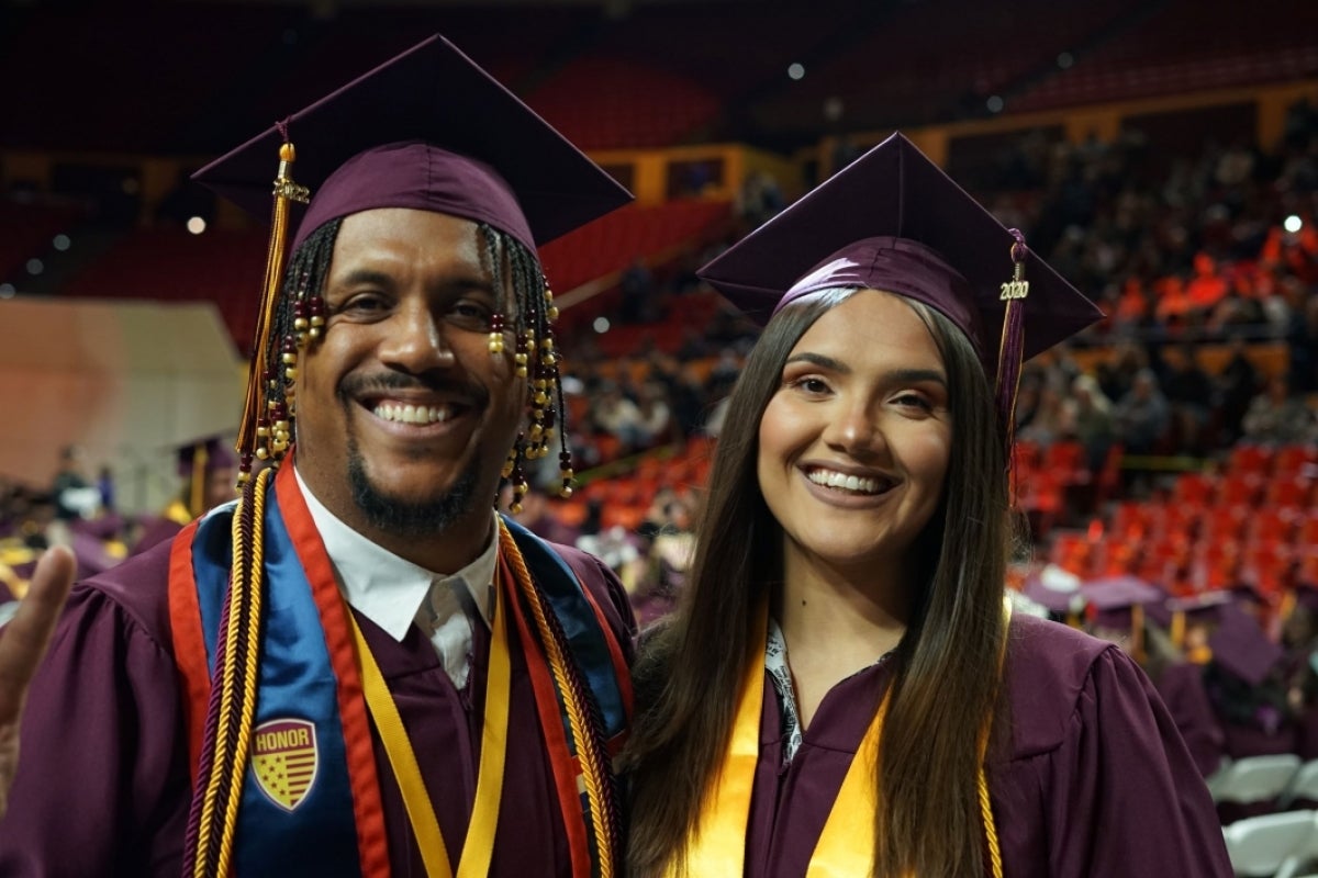 Watts College Outstanding Graduate Kevin Brown-Kaufman poses smiling next to his daughter, Zarina Brown. Both wear ASU graduation regalia.