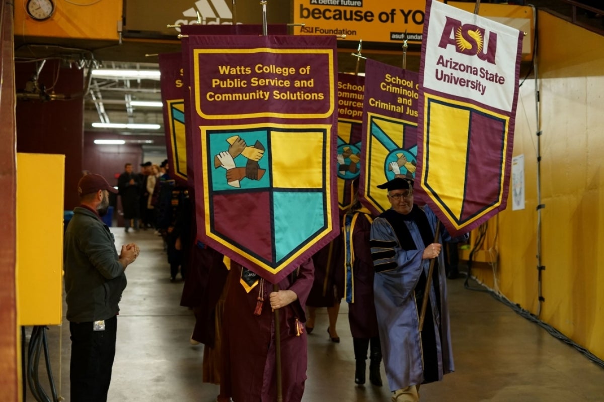 Faculty holding gonfalons at a graduation celebration.