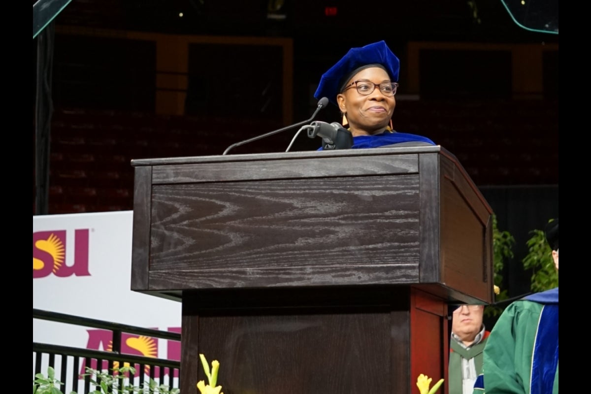 Woman standing behind a lectern looking at a crowd.