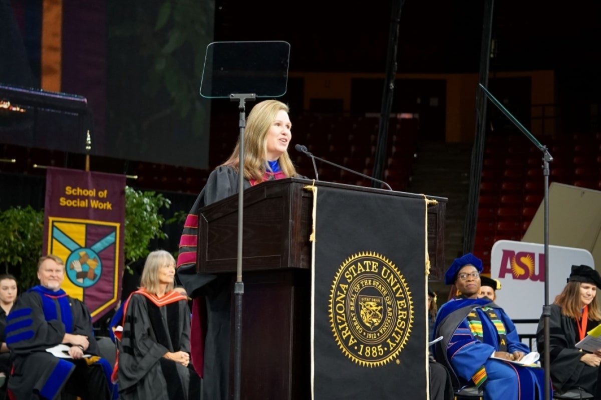 Woman speaking into a microphone behind a lectern.