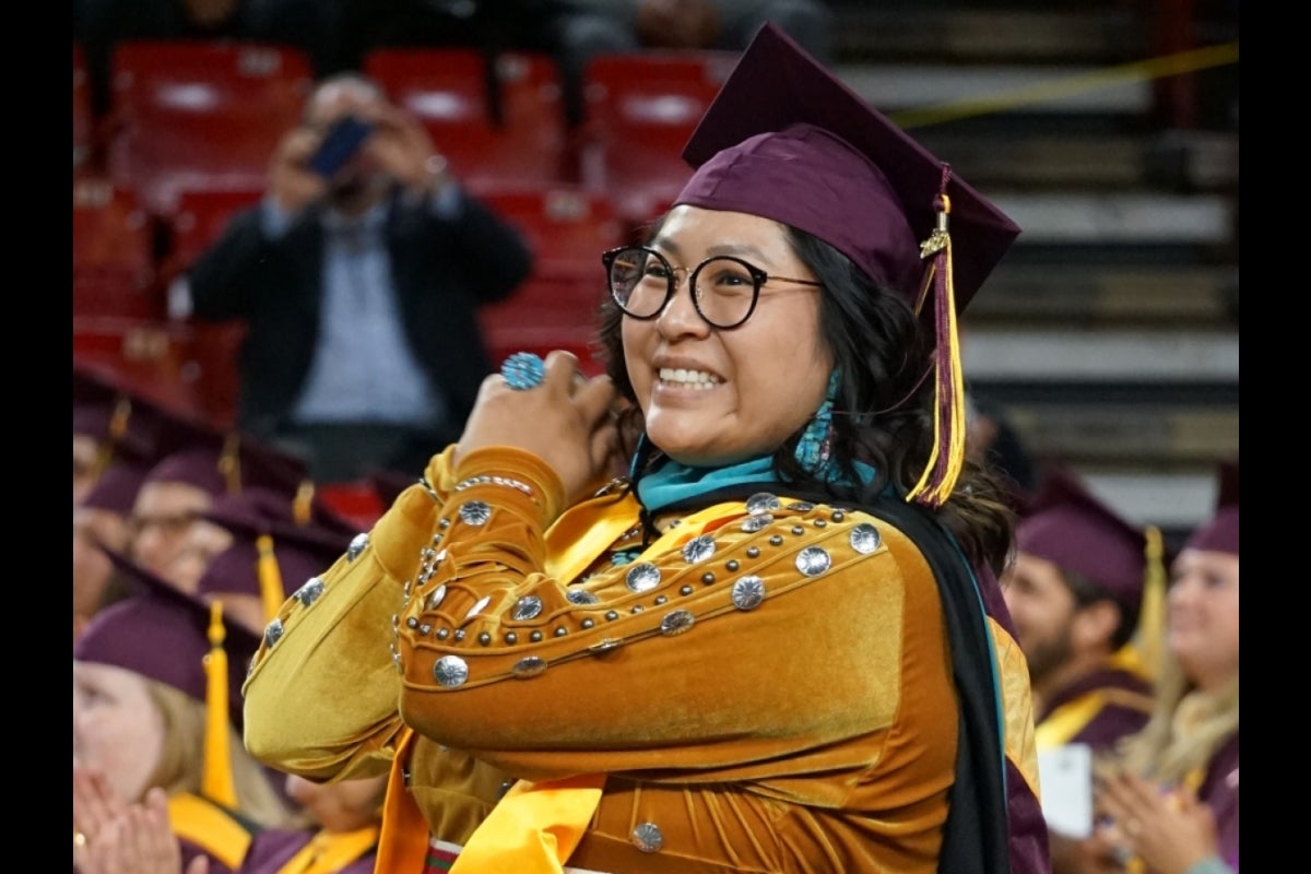 Woman wearing a maroon graduation cap and Native American dress.