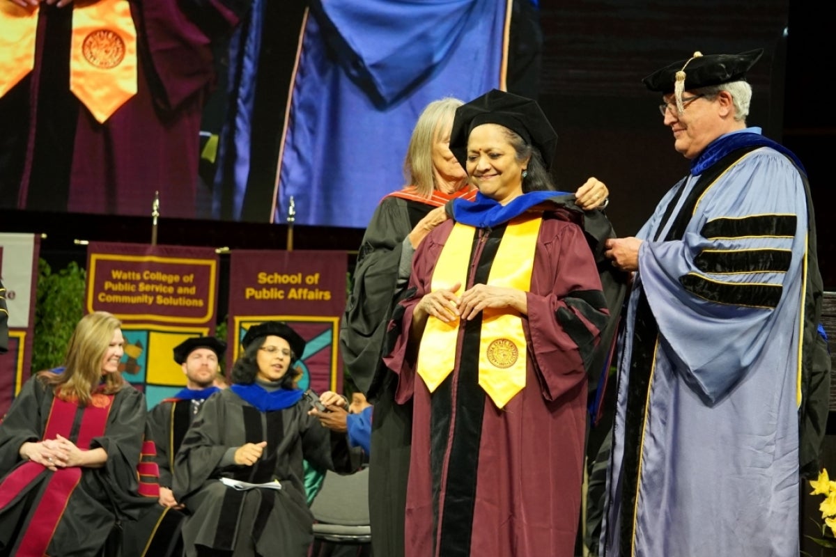 Woman on stage wearing graduation regalia.