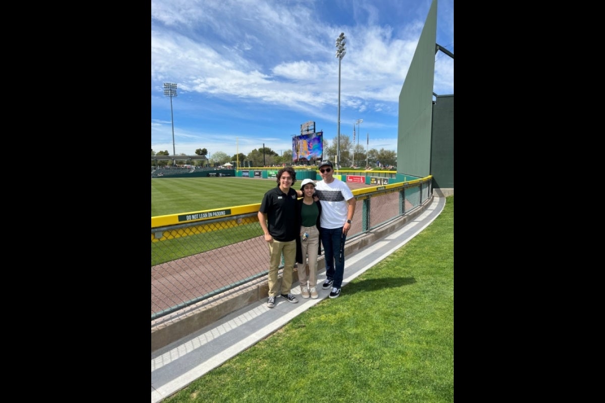 Students posing next to baseball field