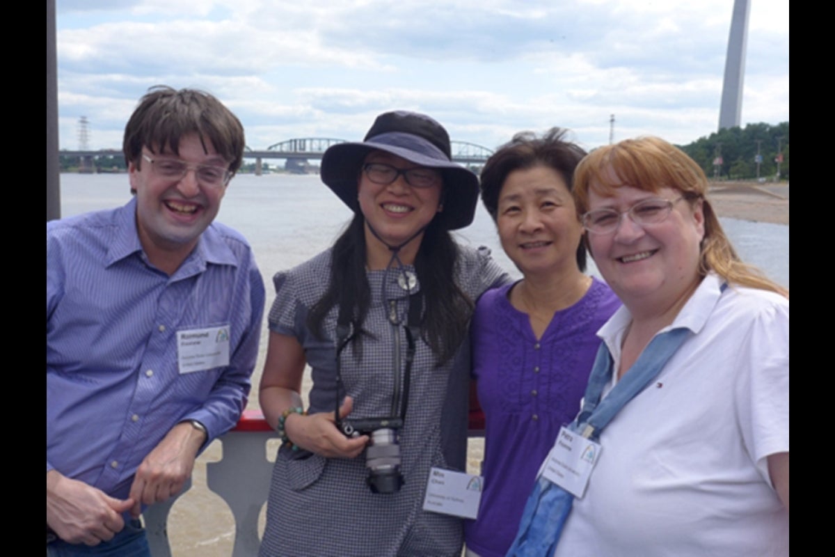 Photo of four people posing in front of river