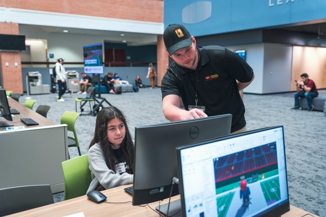 Instructor points to a monitor, which a student is looking at.