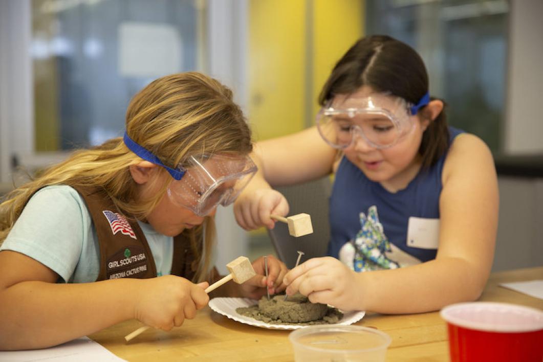 Two Girl Scout members collect materials from hardened sand blocks