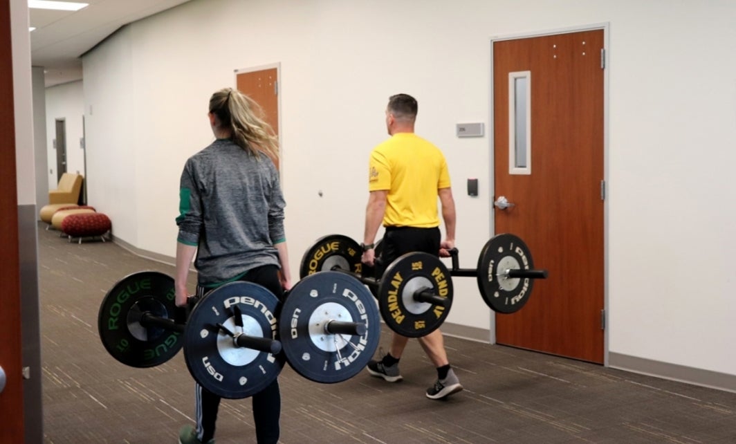 two people carrying weights down hallway