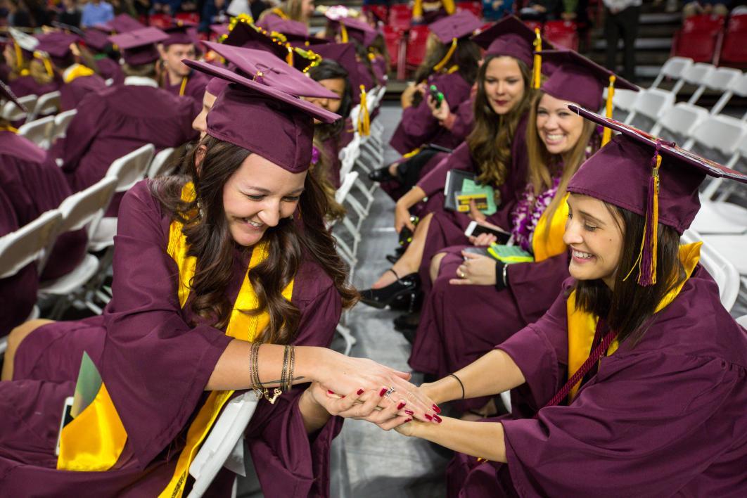 ASU graduate warming hands of another graduate