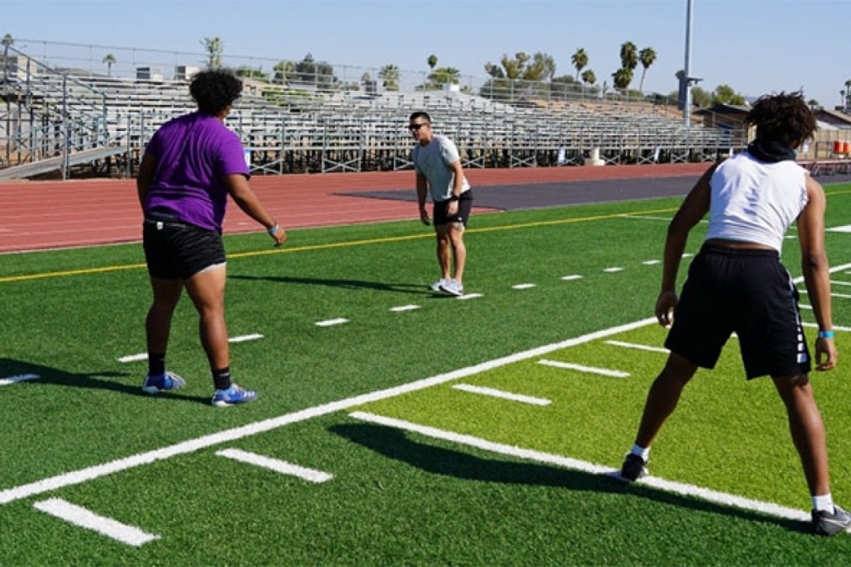 High school students working out on a football field.