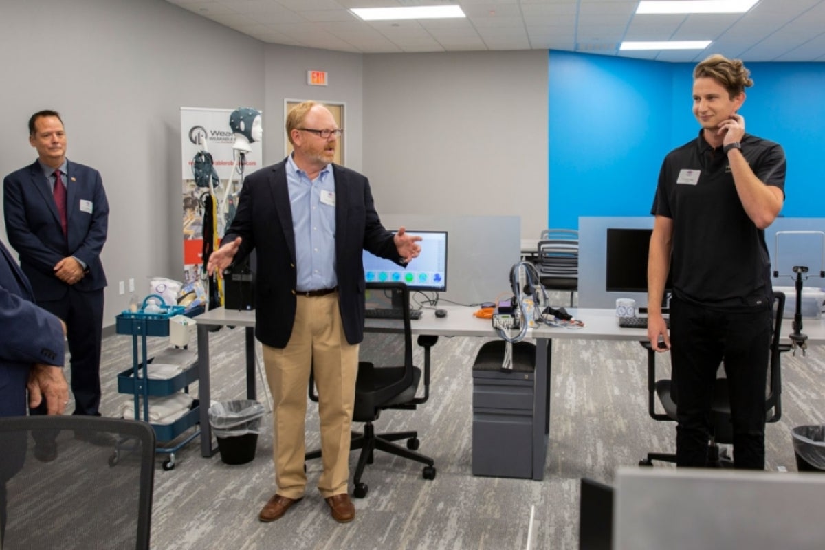 WearTech Applied Research Center Operations Director Wes Gullett (left) introduces Hoolest Performance Technologies to grand opening guests as the company’s co-founder Nick Hool demonstrates the technology.