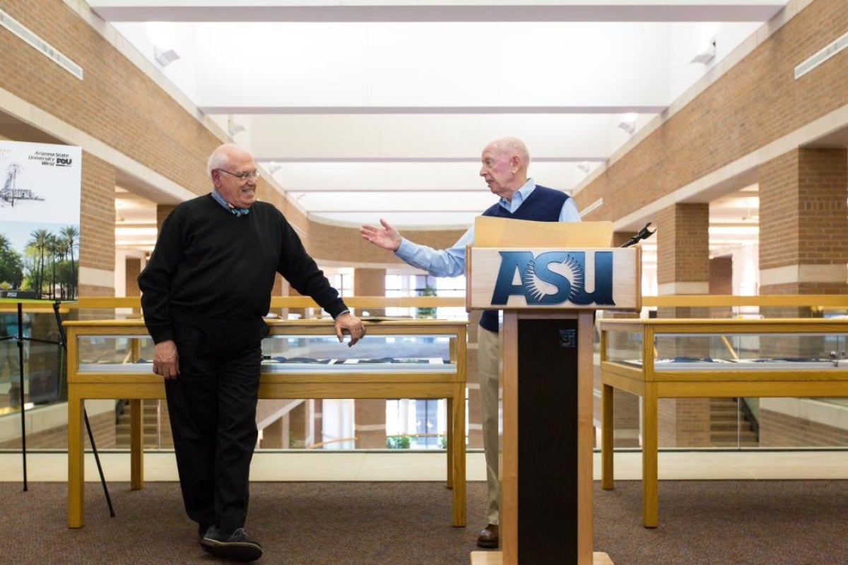 two men speaking at podium