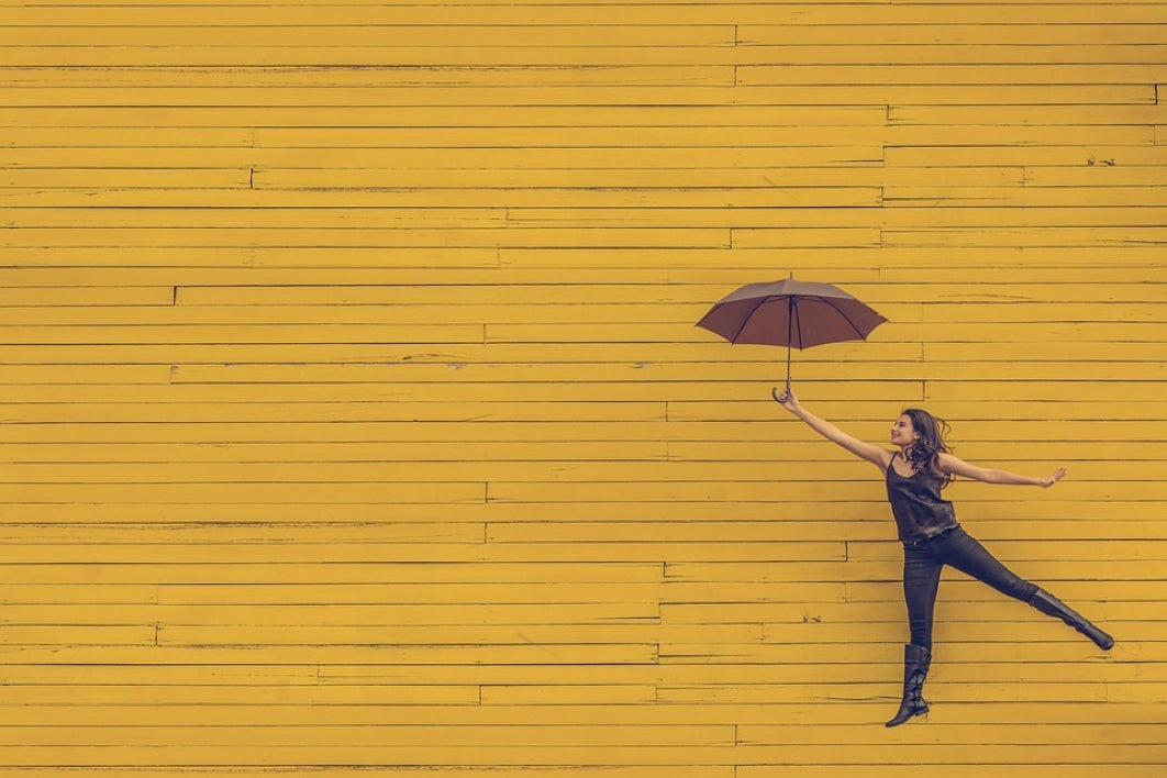 happy woman jumping with umbrella