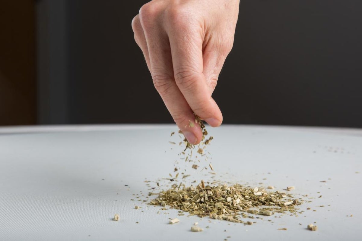 hand sprinkling green leaves on surface