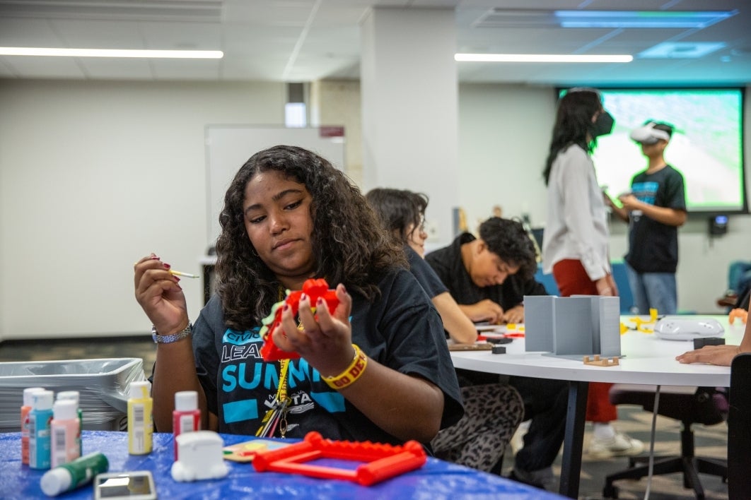 Young girl painting a 3D-printed object.