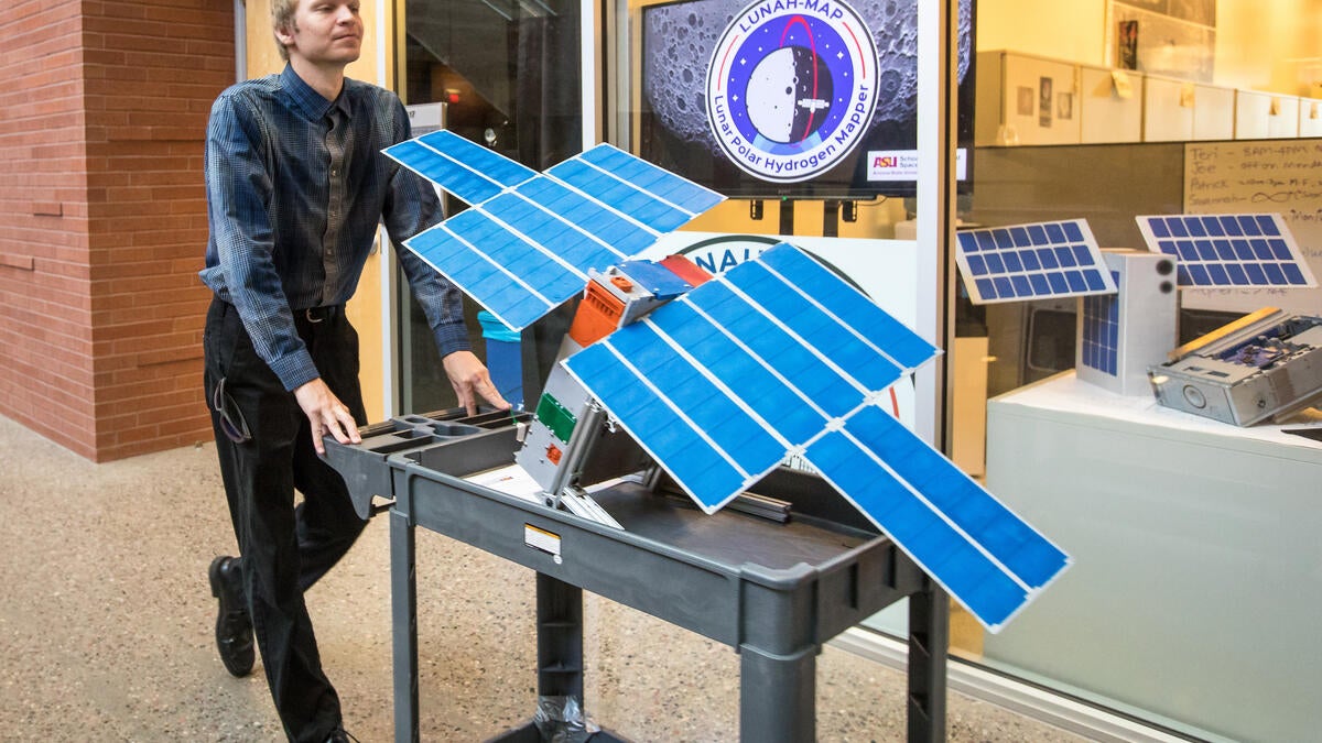 A student wheels a full-scale LunaH-Map model through a hallway