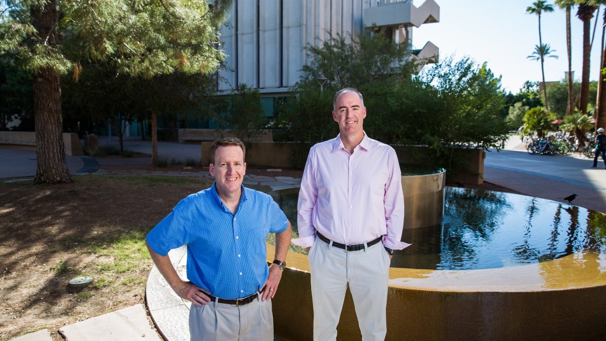 two men standing in front of a fountain