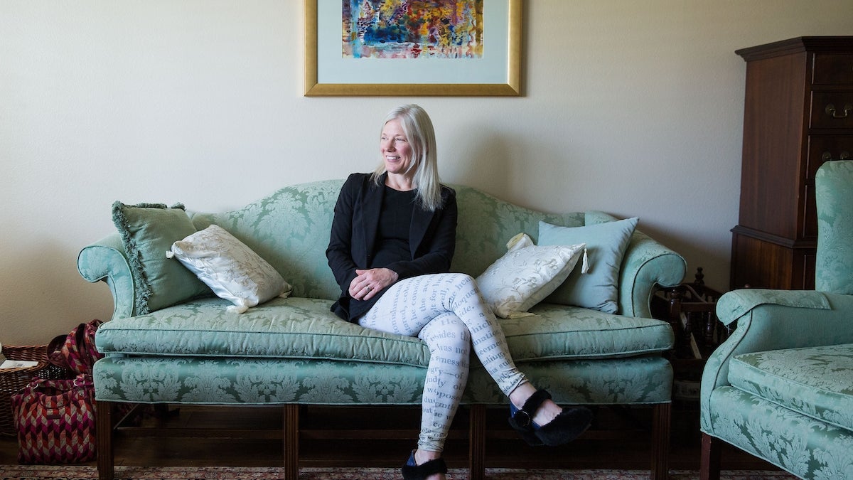 ASU Professor Devoney Looser is pictured seated on a sofa in her living room in her house.