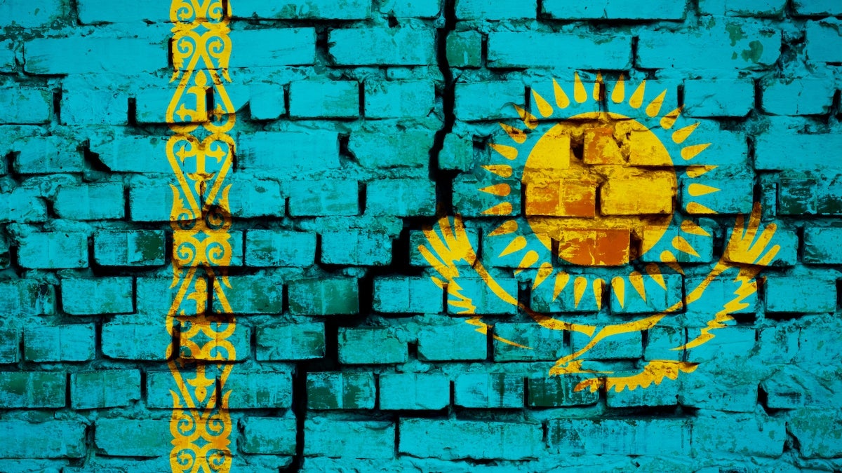 Painting of the flag of Kazakstan on a brick wall with a crack down the middle of it.