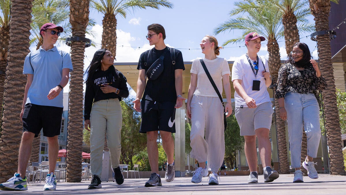 A line of students smiling as they walk on campus