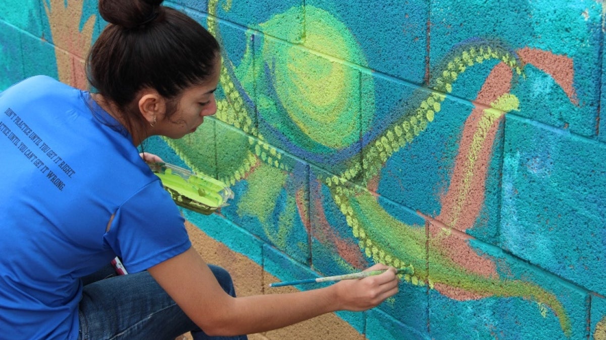 girl in blue shirt paints yellow octopus